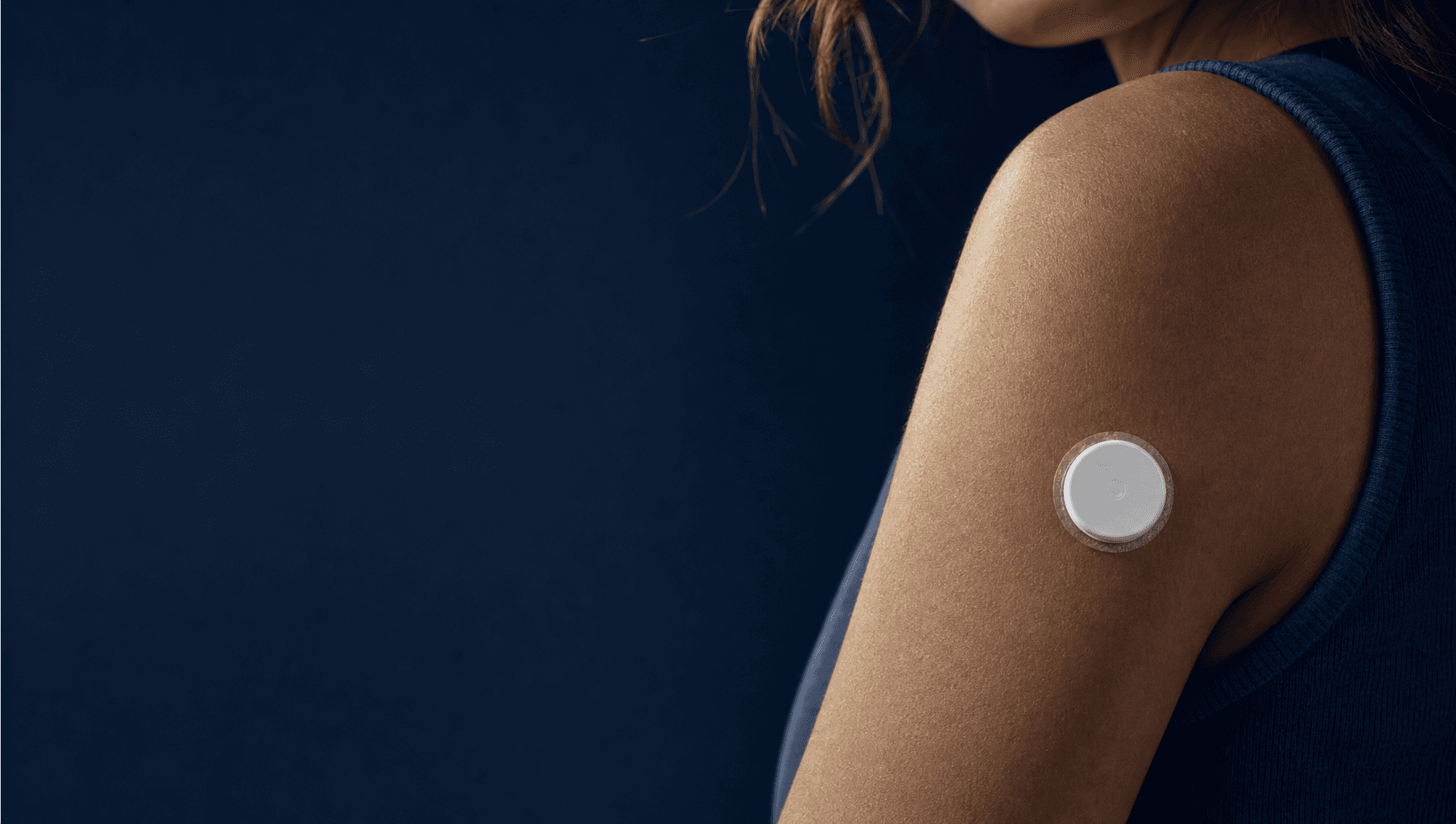 Continuous glucose sensor worn high on the back of the upper arm, skin rim-lit