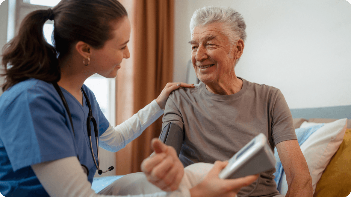 A nurse sitting with an older patient during a blood pressure reading